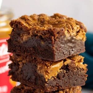 A stack of three brownies with peanut butter on top.